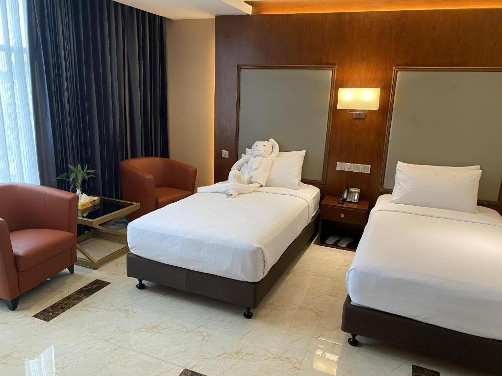 une chambre d'hôtel avec deux lits et une chaise dans l'établissement Hotel Tower Inn, Chittagong, à Chittagong Port