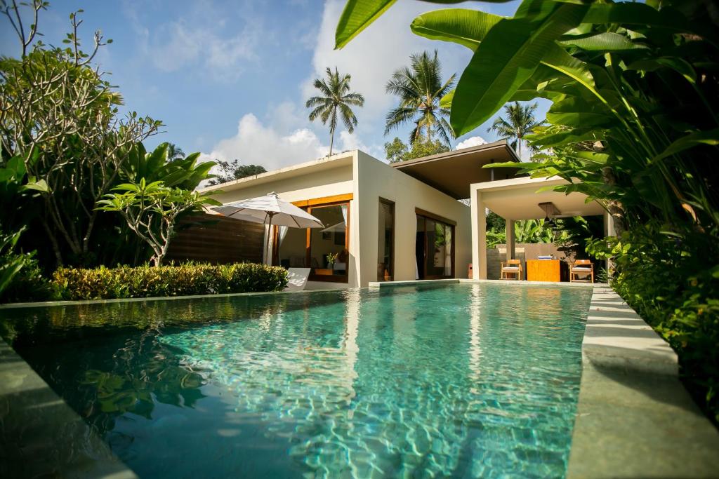 a swimming pool in front of a house at Senetan Villas and Spa Resort in Payangan