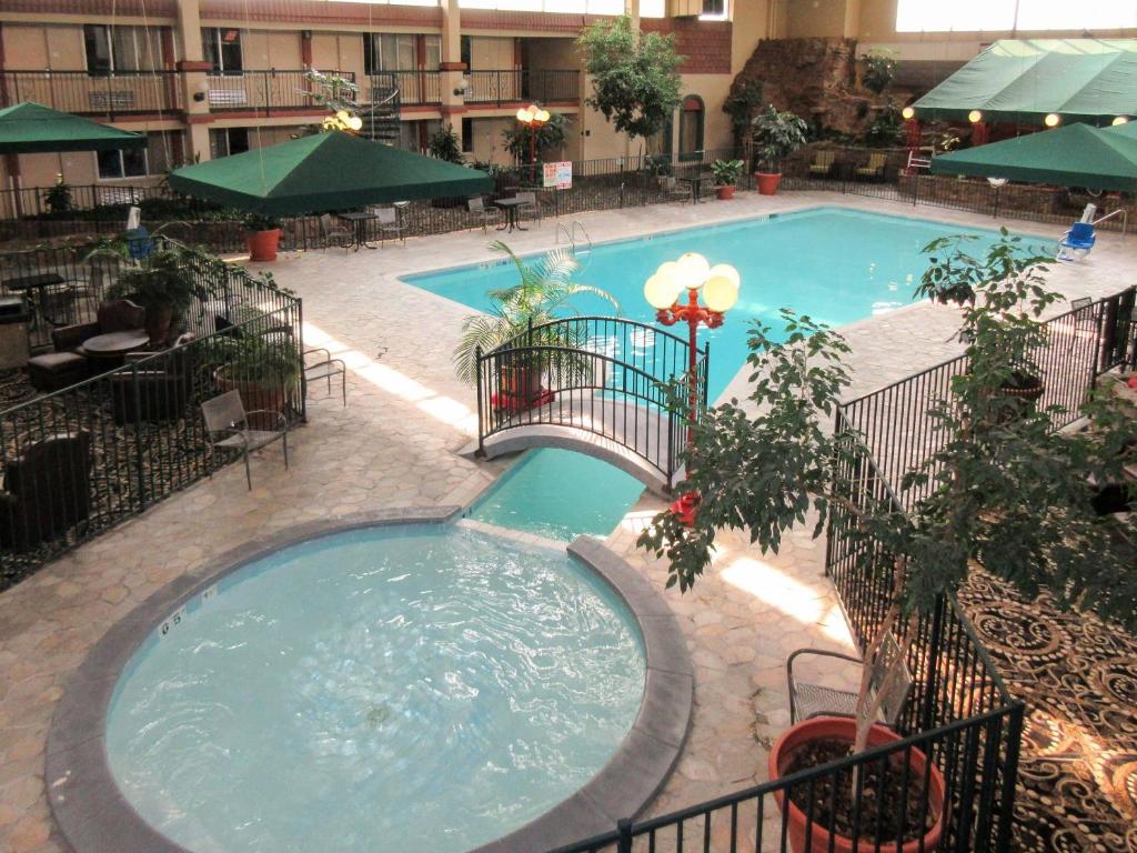 a large swimming pool in a courtyard with tables and umbrellas at Clarion Inn in Fort Collins