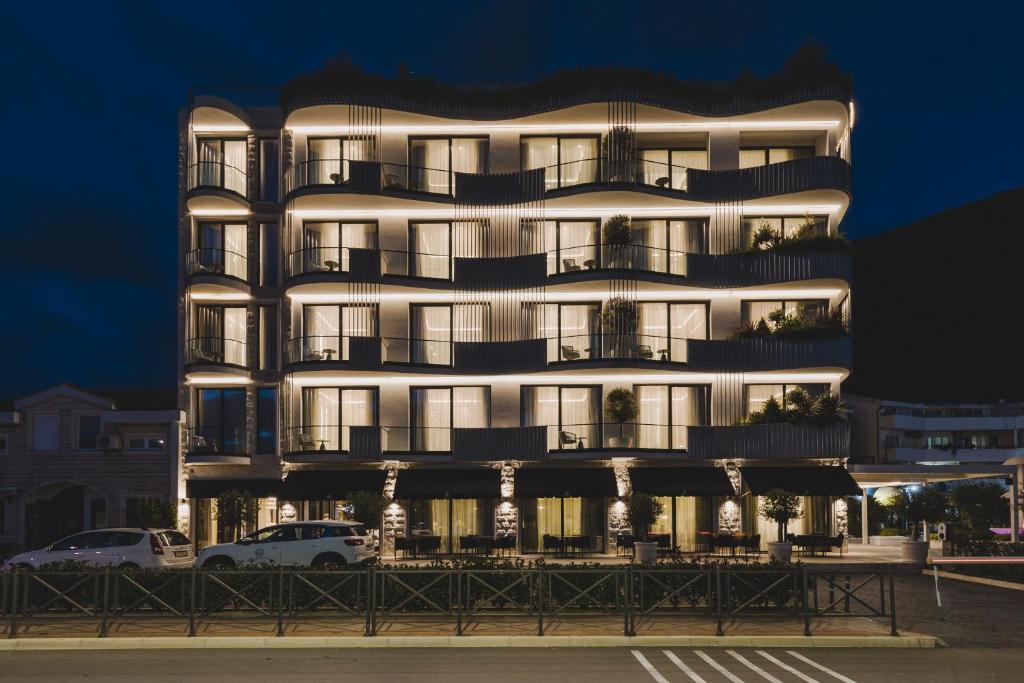 Un edificio alto y blanco con coches aparcados delante. en Luminoso Boutique Hotel, en Budva