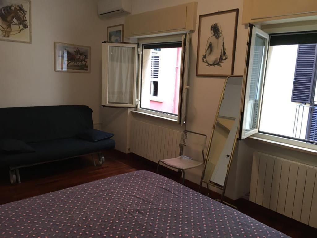 a bedroom with a bed and a couch and two windows at La Casetta in Teramo
