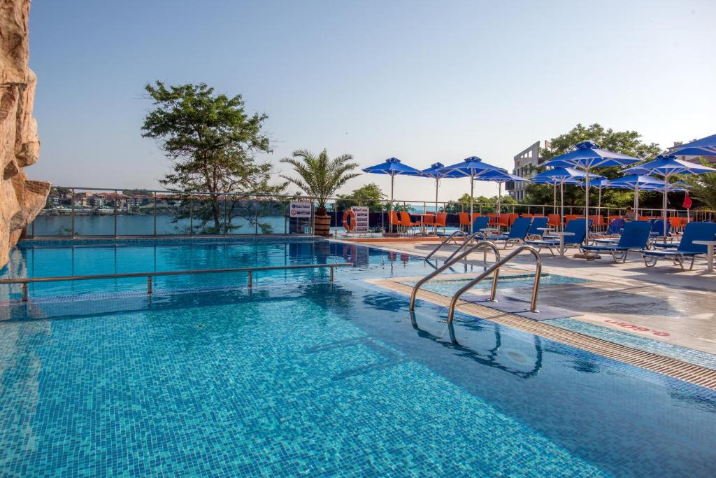 a large swimming pool with blue chairs and umbrellas at Selena Hotel in Sozopol