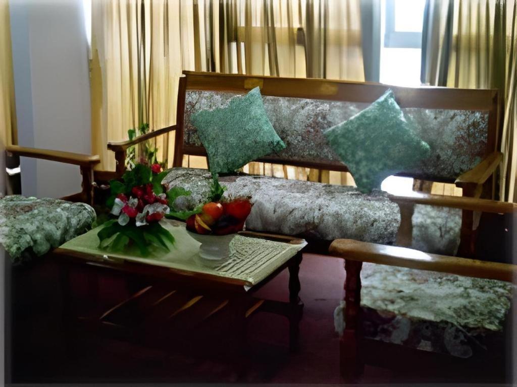 ein Wohnzimmer mit einer Couch und einem Tisch mit Blumen in der Unterkunft Vasu Hotel Mahasarakham in Maha Sarakham