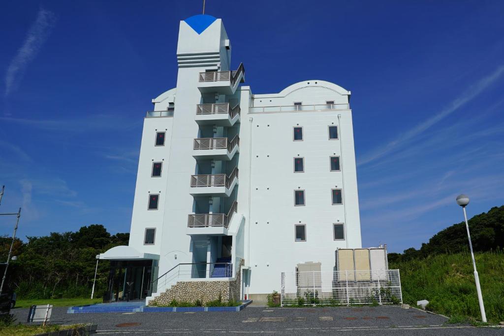 un edificio blanco con una torre de reloj en la parte superior en Tobi Hostel and Apartments, en Shima