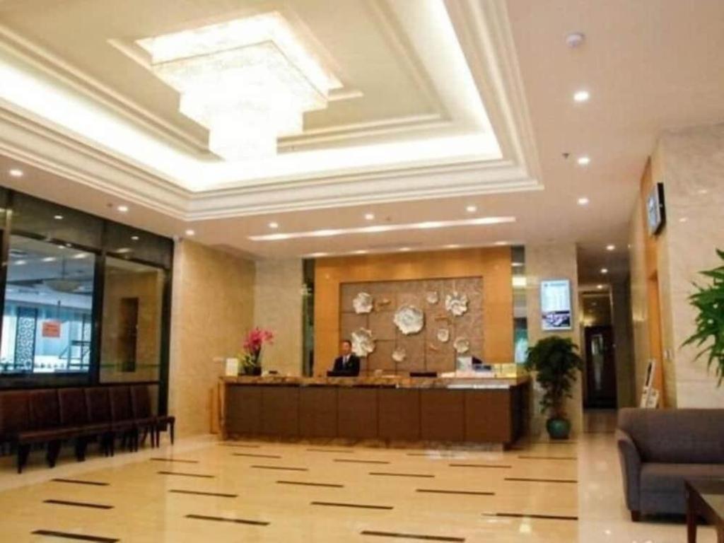 eine Lobby eines Hotels mit einer Person, die an einem Schreibtisch sitzt in der Unterkunft GreenTree Inn GuangDong DongGuan HouJie Business Hotel in Dongguan