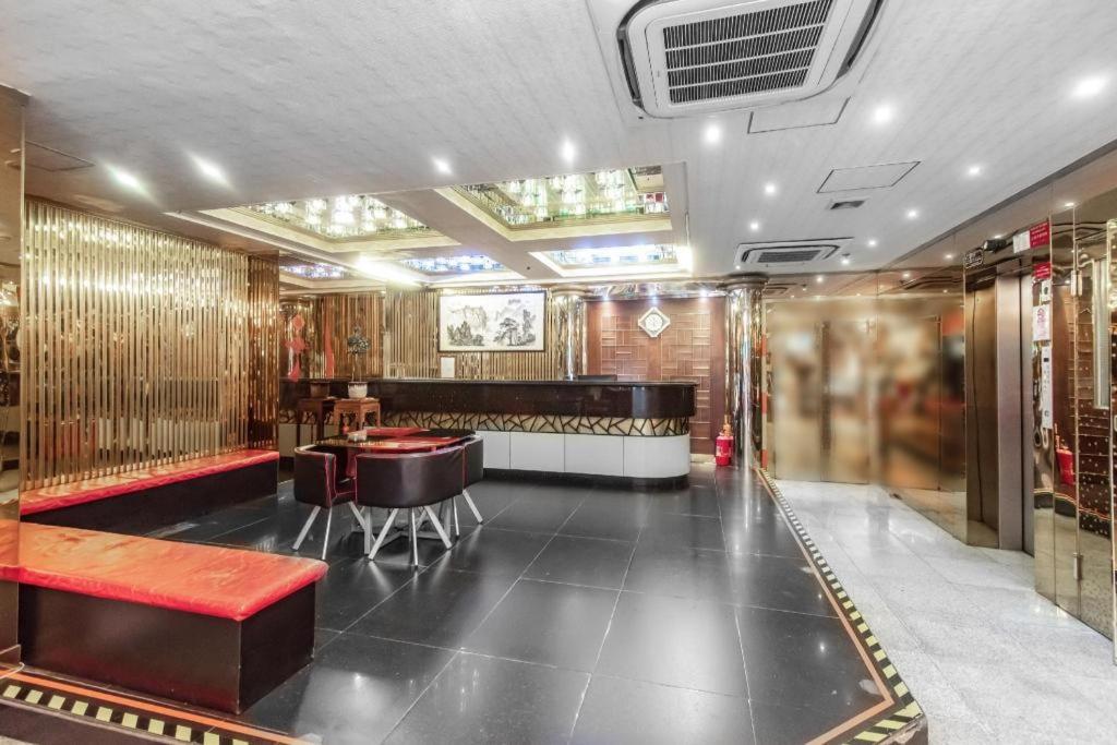 a room with a bar with a red bench and tables at Holiday Hotel in Macau