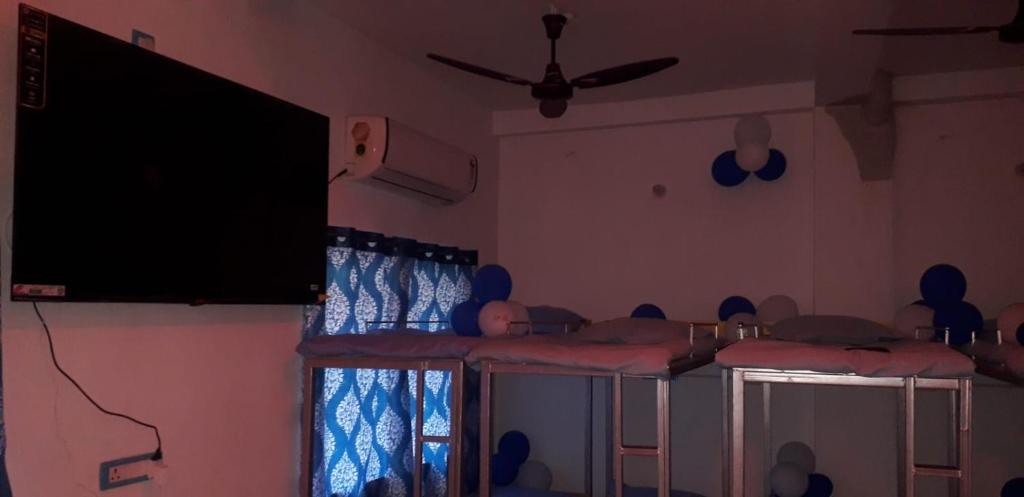 a room with four beds and a flat screen tv at AC Comfort Guest House in Deoghar