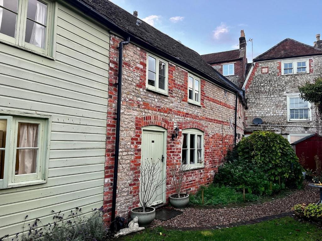 ein Backsteinhaus mit Topfpflanzen davor in der Unterkunft Charming Grade 2 Cottage w/ Garden in Warminster in Warminster