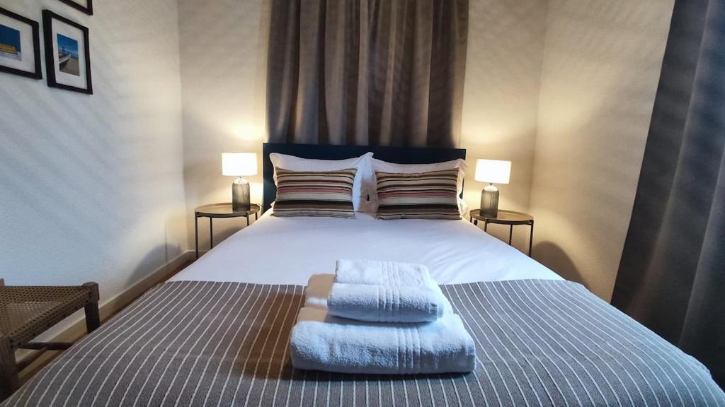 a bedroom with a large white bed with two lamps at SixtyNine Beach Cottage in Torreira