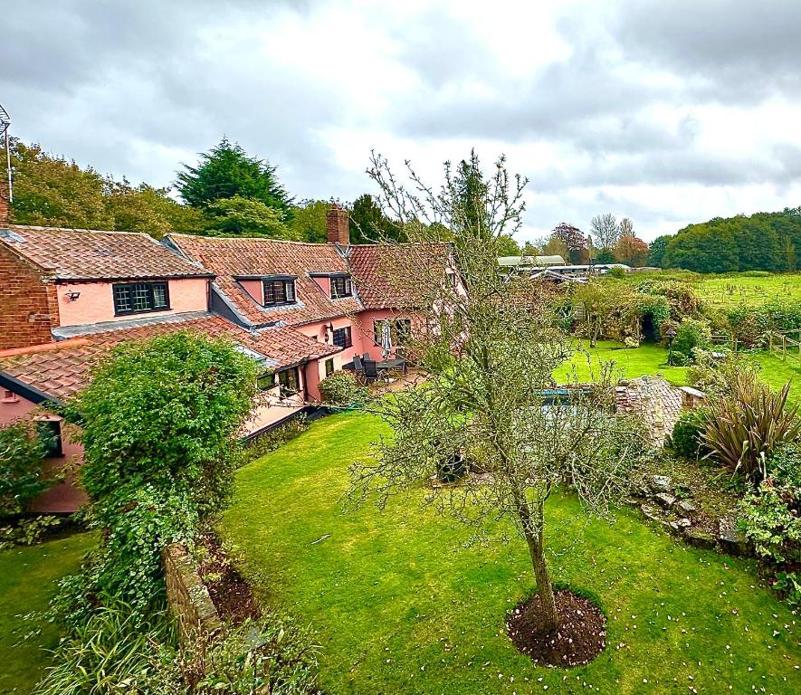 ein altes Haus mit einem Baum im Hof in der Unterkunft Danegelts Waveney Marshes Bed & Breakfast in Geldeston