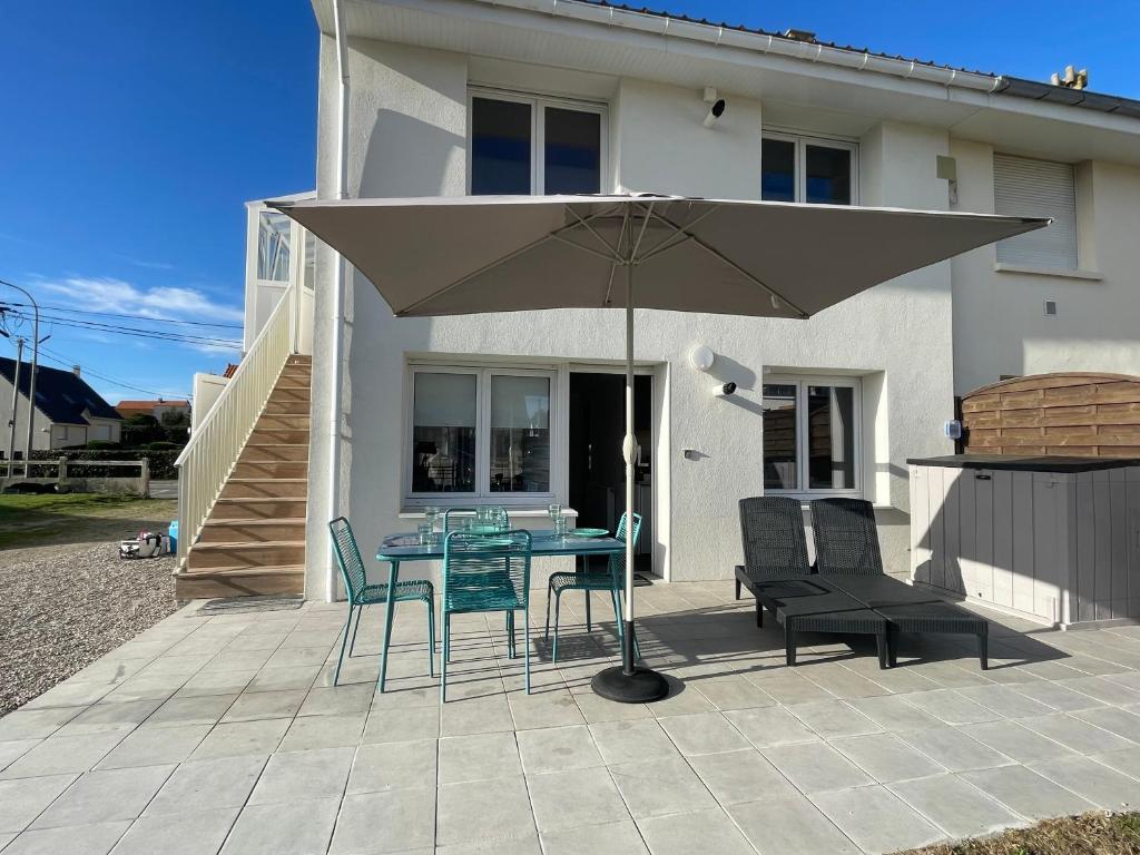 a patio with a table and chairs and an umbrella at Ste Cécile Plage in Camiers