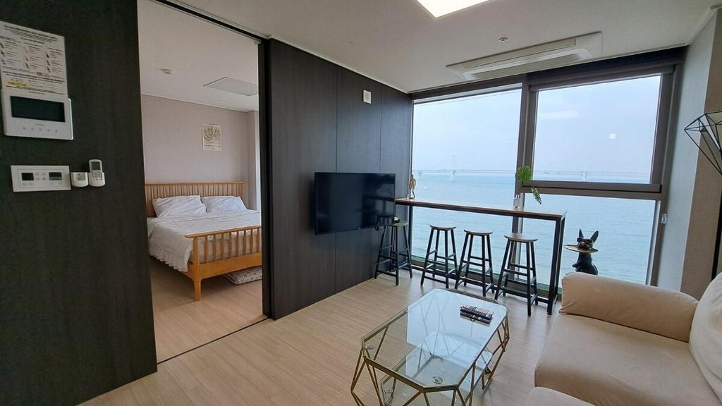 a living room with a bed and a view of the ocean at Charman Ocean View Sunrise 10 seconds to the beach in Kwangan-dong