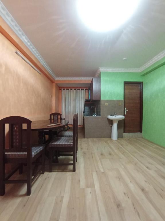 Un comedor con mesa y sillas y una cocina. en Maskey Niwas, en Katmandú