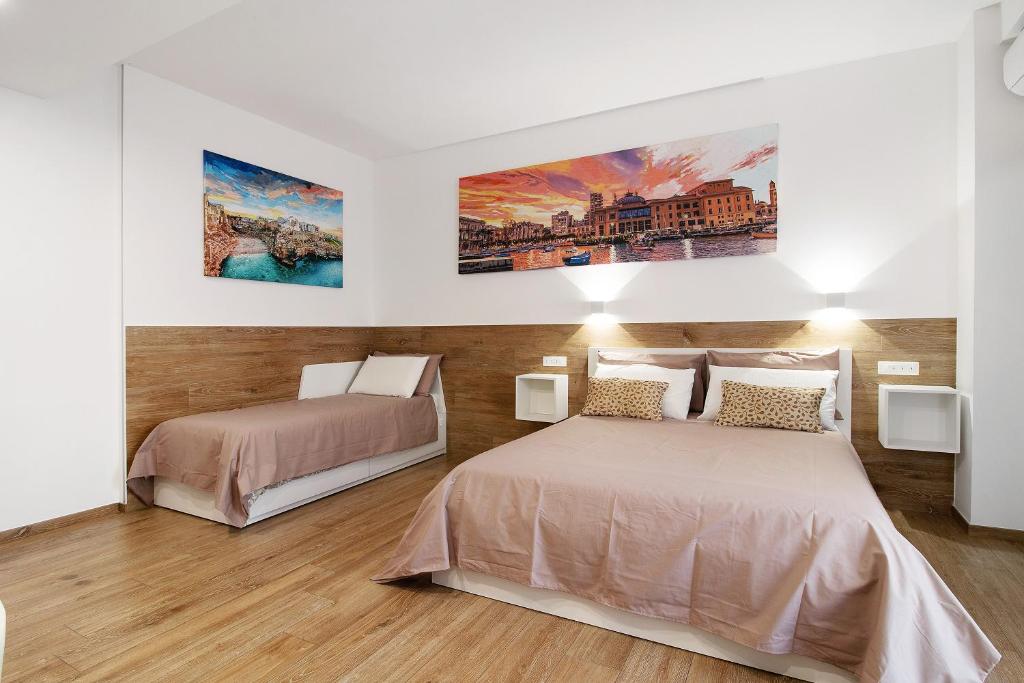 een slaapkamer met 2 bedden en 2 schilderijen aan de muur bij Gold - Il Centro Luxury Suites in Bari