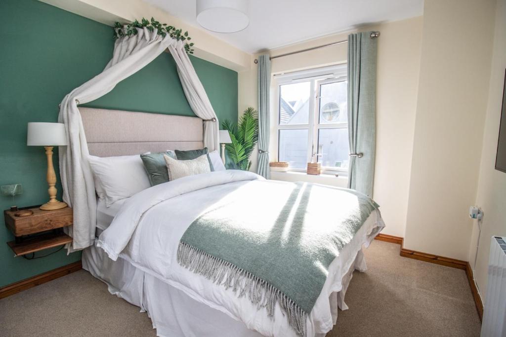 ein Schlafzimmer mit einem weißen Bett mit Himmelbett in der Unterkunft 5 Star Luxury Apartment in the Heart of Galway City in Galway