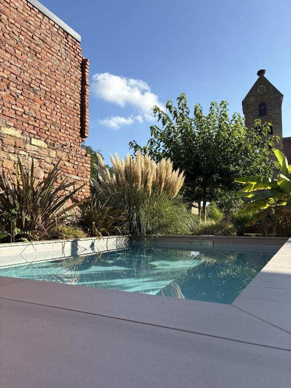 a swimming pool in front of a brick building at A l'ancienne boulangerie, proche de Colmar et des plus beaux villages en Alsace in Meyenheim