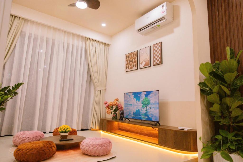 un salon avec une télévision et des poufs roses dans l'établissement Châu Giang Luxury -Nera Garden APartment 2-3 Bedroom, FREE hồ bơi, à Hue