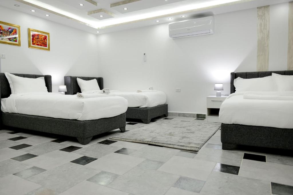 two beds in a room with white walls at Rose In Apartment in Wadi Musa