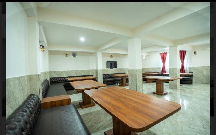 ein Restaurant mit Tischen und Sofas in einem Raum in der Unterkunft Padmashree Hotel & Spa in Darjeeling