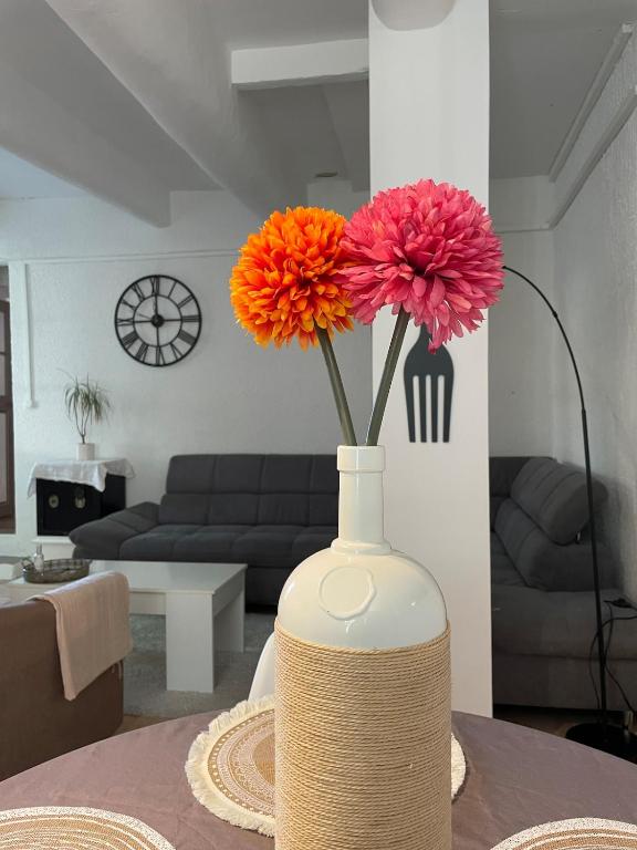 a white vase with flowers in a living room at Gîte au cœur des vignes, près du canal du Midi in Capestang