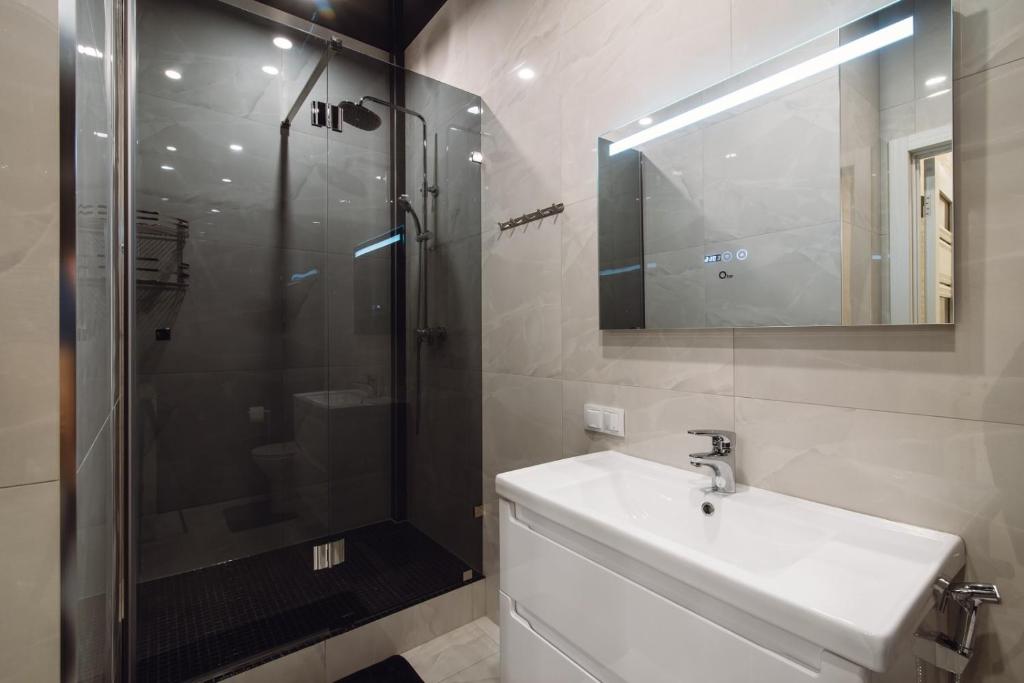 une salle de bains avec douche, lavabo et miroir dans l'établissement АПАРТАМЕНТЫ МОРЕе, à Odessa
