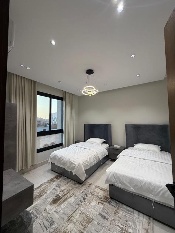 ein Schlafzimmer mit zwei Betten und einem großen Fenster in der Unterkunft سكاي هوم السلامة in Dschidda