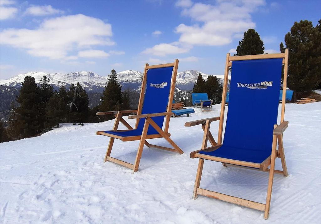 a couple of chairs sitting in the snow at Modernes Apartment - Nockberge in Ebene Reichenau