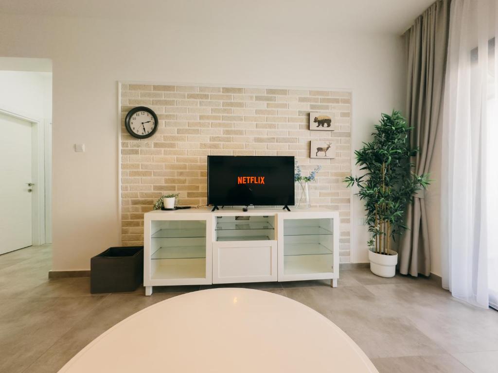 ein Wohnzimmer mit Fernseher und einer Ziegelwand in der Unterkunft Caesar Resort 2 Bedroom Deluxe Home in Iskele