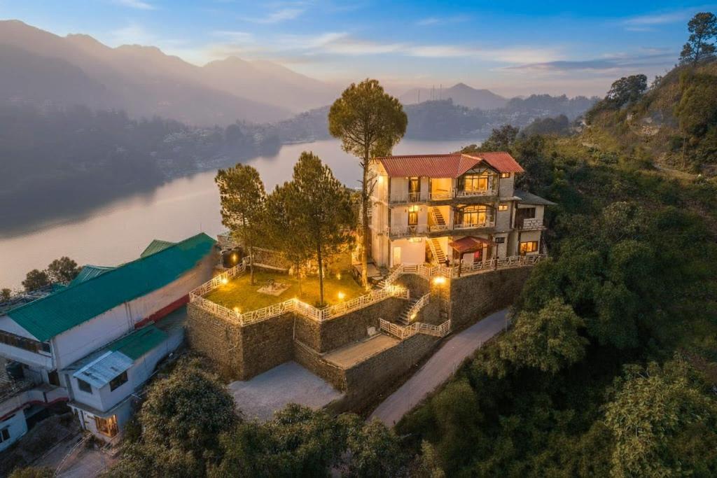 una vista aerea di una casa su una collina accanto a un fiume di Cottage On The Lake by VEO - Part of StayVista a Bhimtal