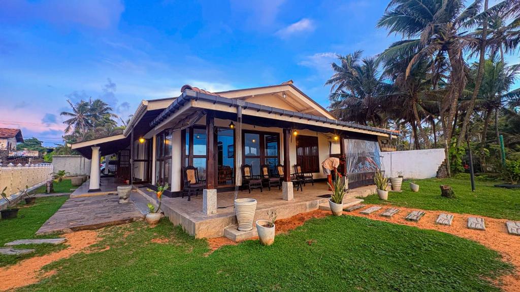 ein kleines Haus mit Veranda und Rasen in der Unterkunft Samudura Beach House, Owakanda in Ratgama Hegoda