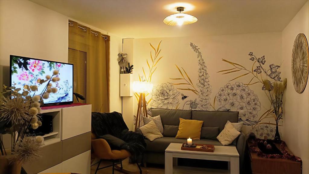 Una sala de estar con un sofá y un televisor de pantalla plana. en Panoramique floral au cœur des illuminations Noël, en La Gacilly