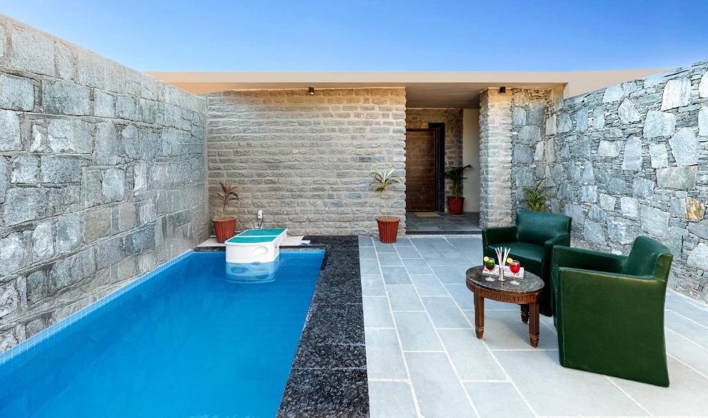 a pool in a patio with two chairs and a table at Jal Dhara Resort in Kumbhalgarh