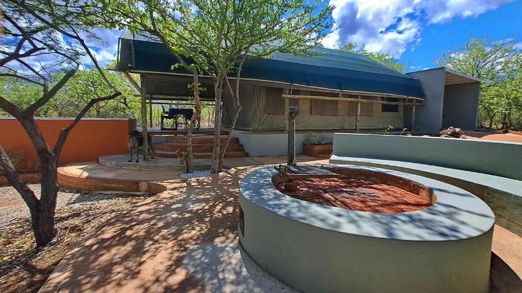 einen Garten mit einer Feuerstelle vor einem Gebäude in der Unterkunft Zuri Camp - Tent Kiama in Tsumeb