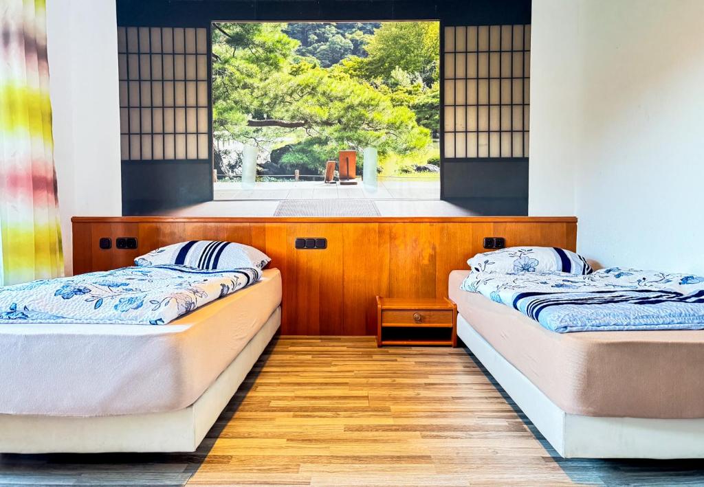 two beds in a room with a window at Hotelkamer voor twee personen in Bunkenburg