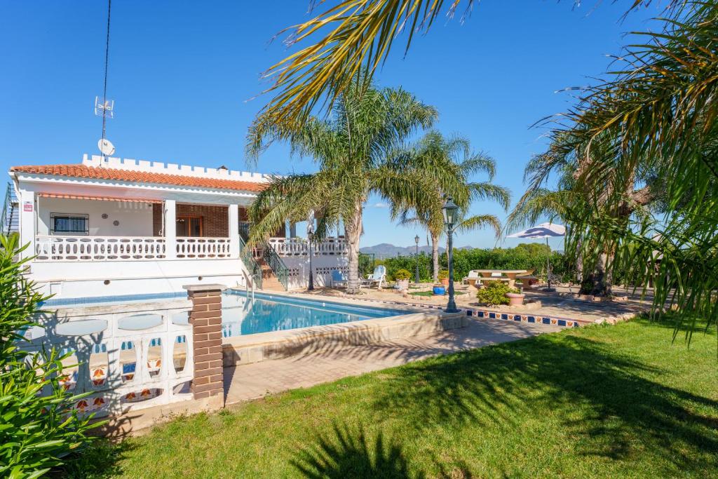 a villa with a swimming pool and palm trees at Masia Miliuca Paraíso rural a un paso de Valencia - Rural paradise close to Valencia in Bétera