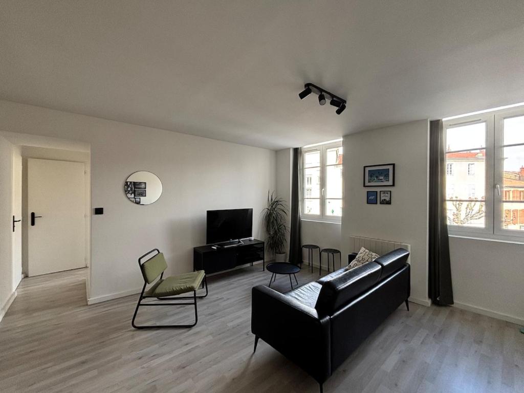 - un salon avec un canapé noir et des chaises dans l'établissement Appartement lumineux & moderne au cœur de Valence, à Valence