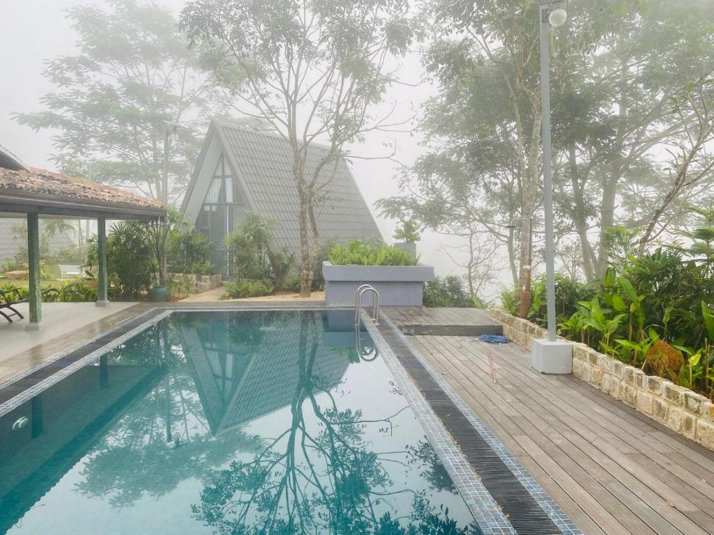 a swimming pool with a wooden deck and a house at Rain Drops Wellness Villa Deniyaya, Sinharaja in Deniyaya
