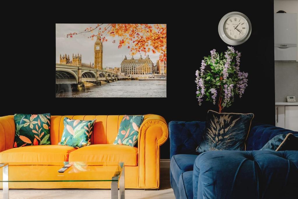 a living room with a yellow couch and a clock at 4-BR House Near-Harry Potter-SkyStudios1-Family & Work Stays in Borehamwood