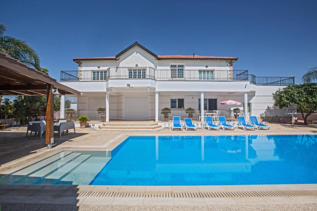 a villa with a swimming pool in front of a house at Papas Family Villa in Paralimni
