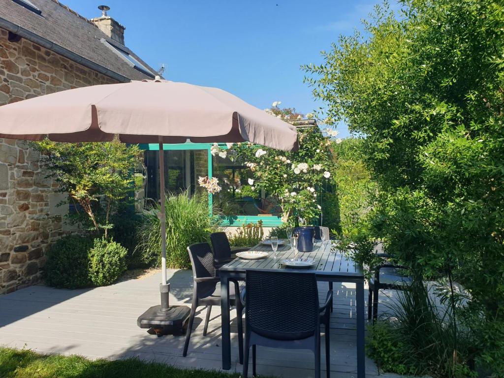 a table and chairs under an umbrella on a patio at Les Coquelicots classé 3 étoiles in Paimpol