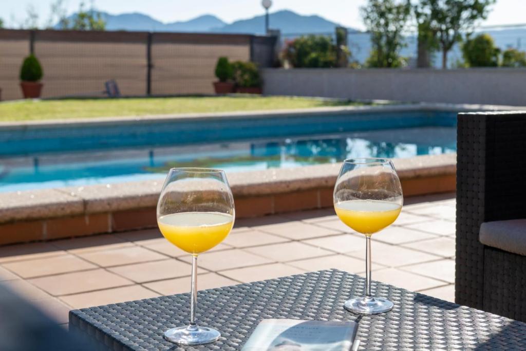 two glasses of wine sitting on a table next to a pool at Abetos Panxon in Nigrán