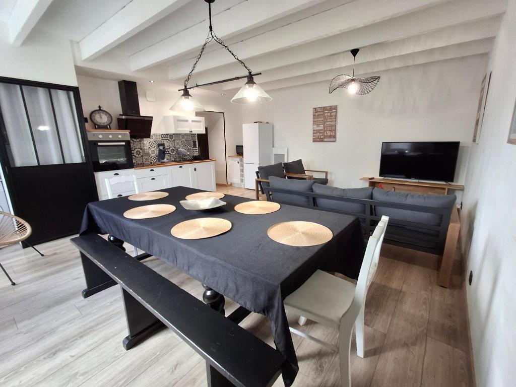 a dining room and kitchen with a black table and chairs at Gîte "Chez Marcel et Cie" - 8 mn du Puy du Fou in Les Herbiers