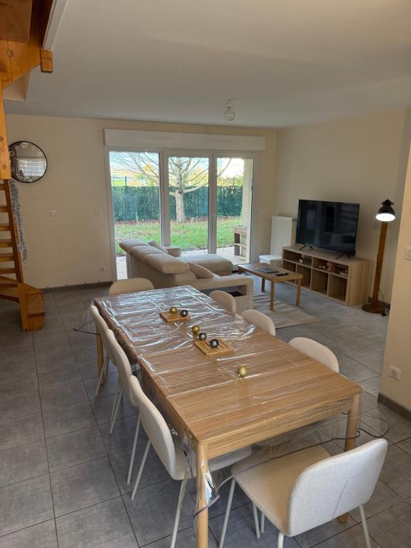 un soggiorno con tavolo e sedie in legno di Maison vue sur le lac et proche du golf ! a Bourges