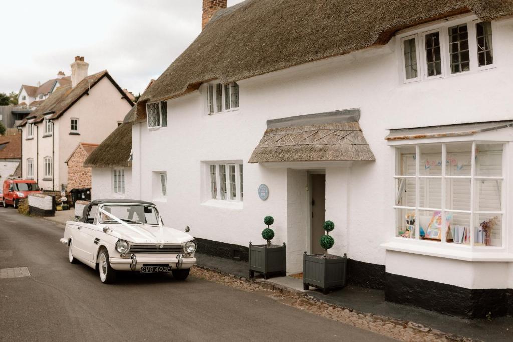ein weißes Auto, das vor einem weißen Haus parkt in der Unterkunft The Old Sweet Shop in Minehead