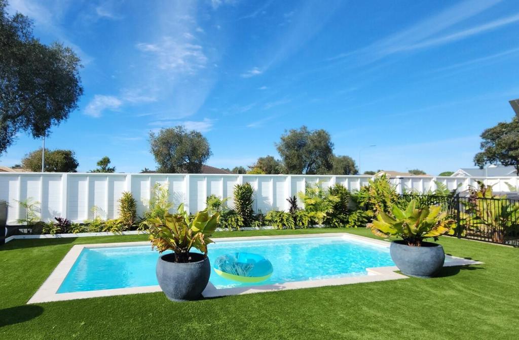 Una piscina en un patio con dos plantas en macetas. en The Weekend, en Papamoa