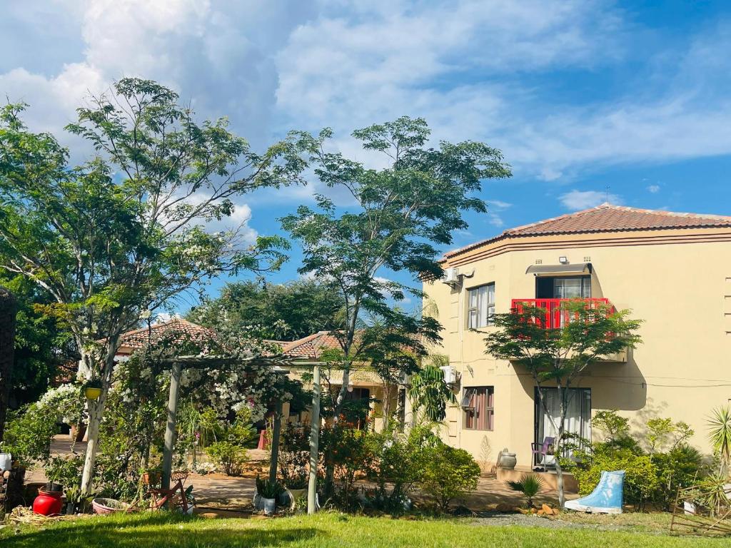 une maison avec une fenêtre rouge sur le côté dans l'établissement Real Favour Suites Guest House, à Palatswe