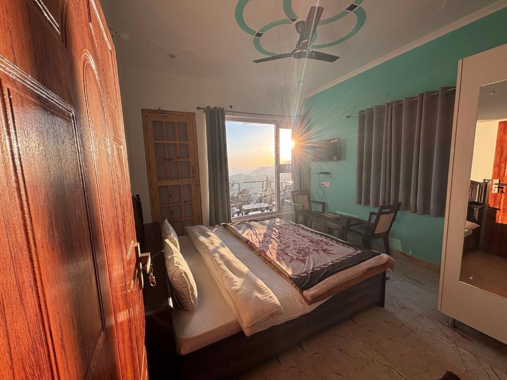 Un dormitorio con una cama y una ventana grande en Hotel Goludev Valley View, en Nainital