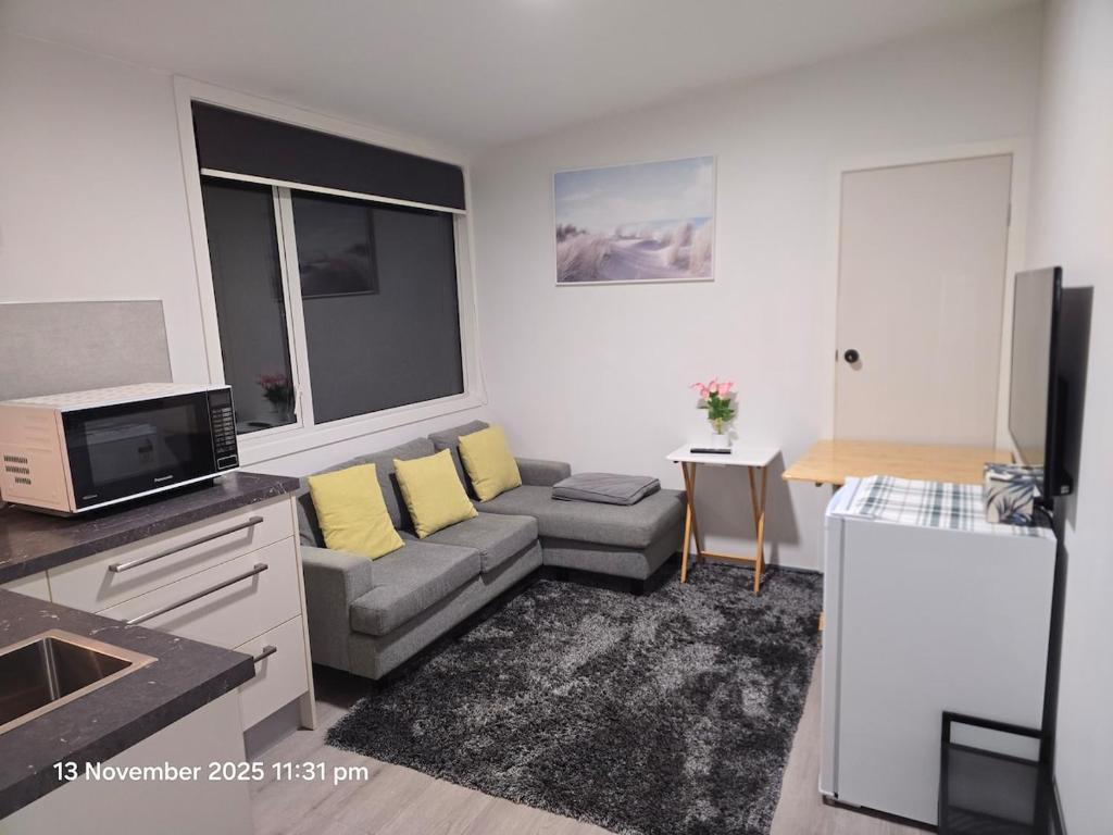 ein Wohnzimmer mit einer grauen Couch und gelben Kissen in der Unterkunft Manuki Tiny Retreat - Private stay Christchurch in Christchurch