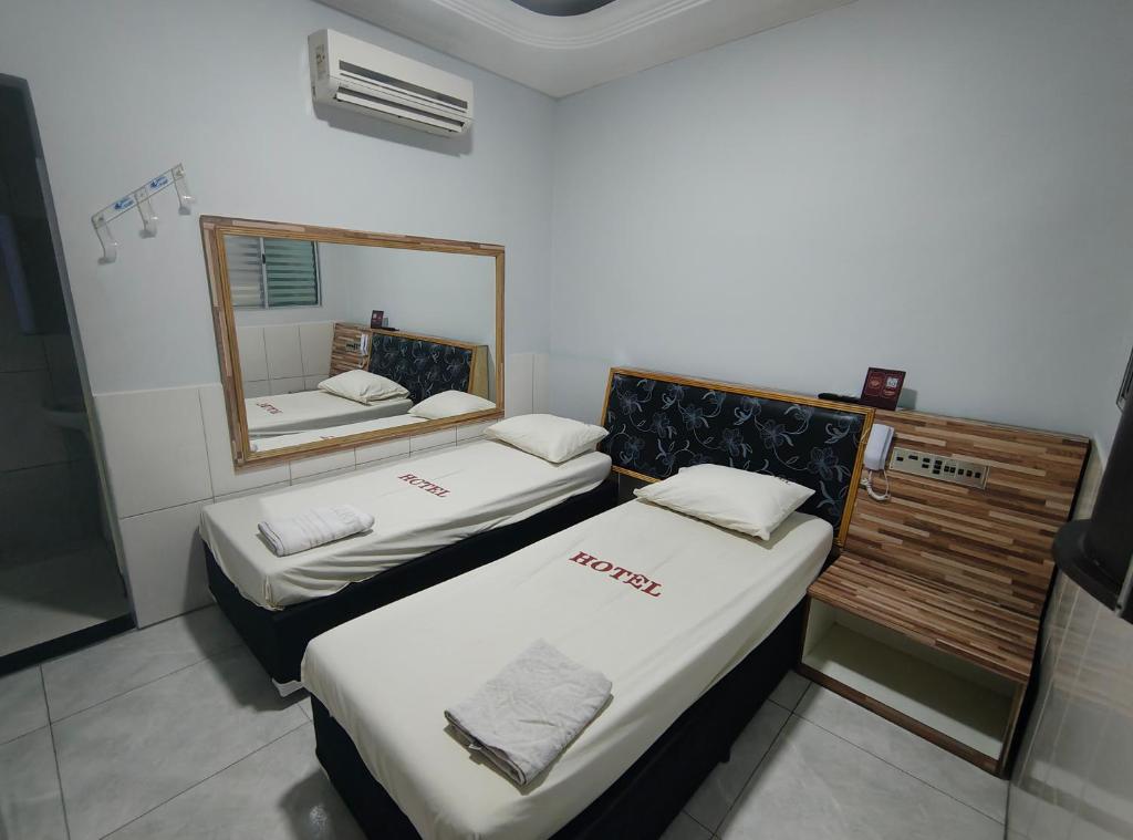 two beds in a small room with a mirror at Hotel Flert Santana in Sao Paulo