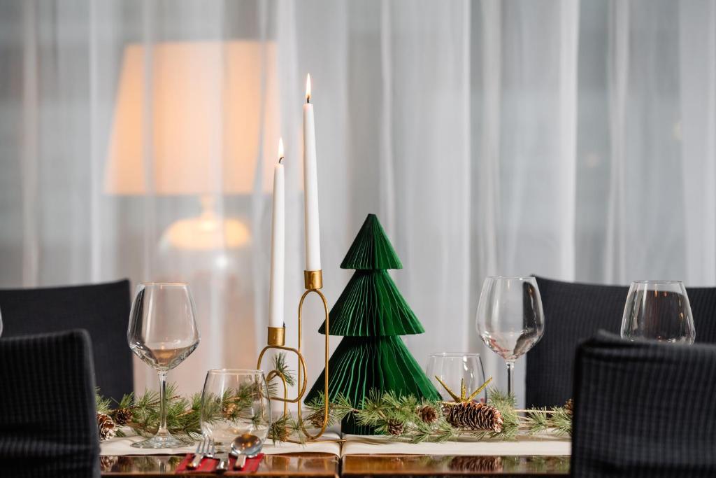a table with a green christmas tree and wine glasses at Europa Royale Bucharest in Bucharest